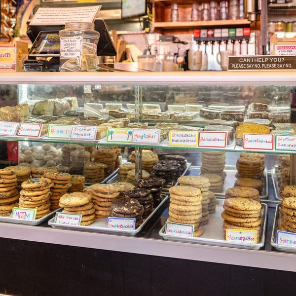 A bakery display case filled with various cookies, brownies, and banana bread loaves.