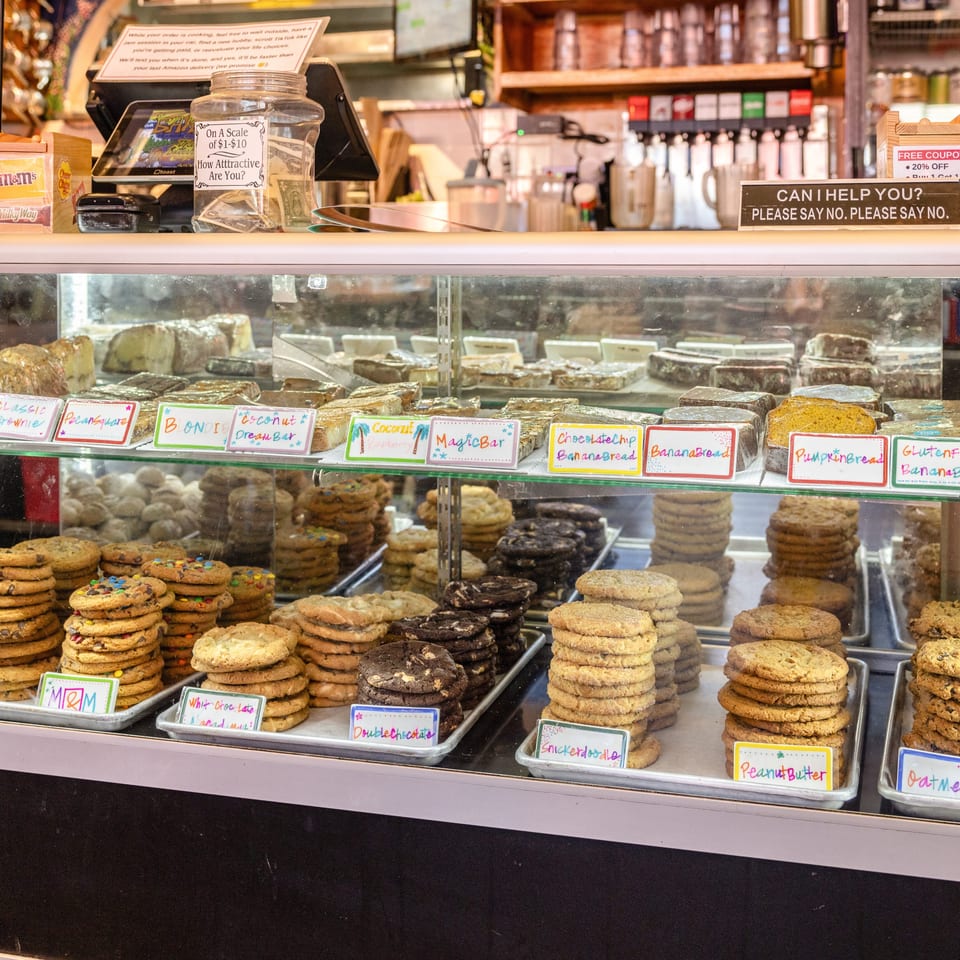 A bakery display case filled with various cookies, brownies, and banana bread loaves.