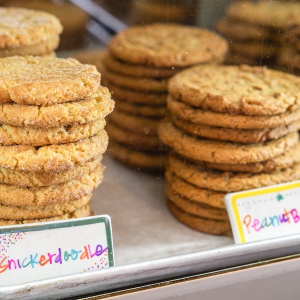 Stacks of Snickerdoodle and Peanut Butter cookies displayed in a bakery case.