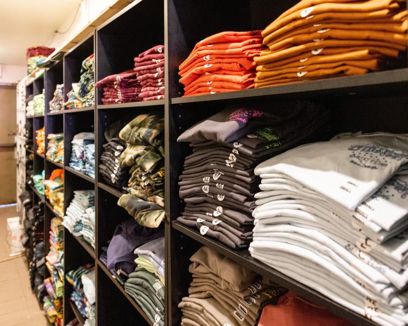 Shelves filled with neatly folded t-shirts and sweatshirts in various colors and patterns.