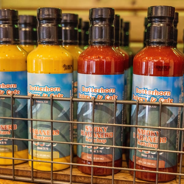 Bottles of Butterhorn Bakery & Cafe's habanero mustard and smoky habanero ketchup in a wire basket.